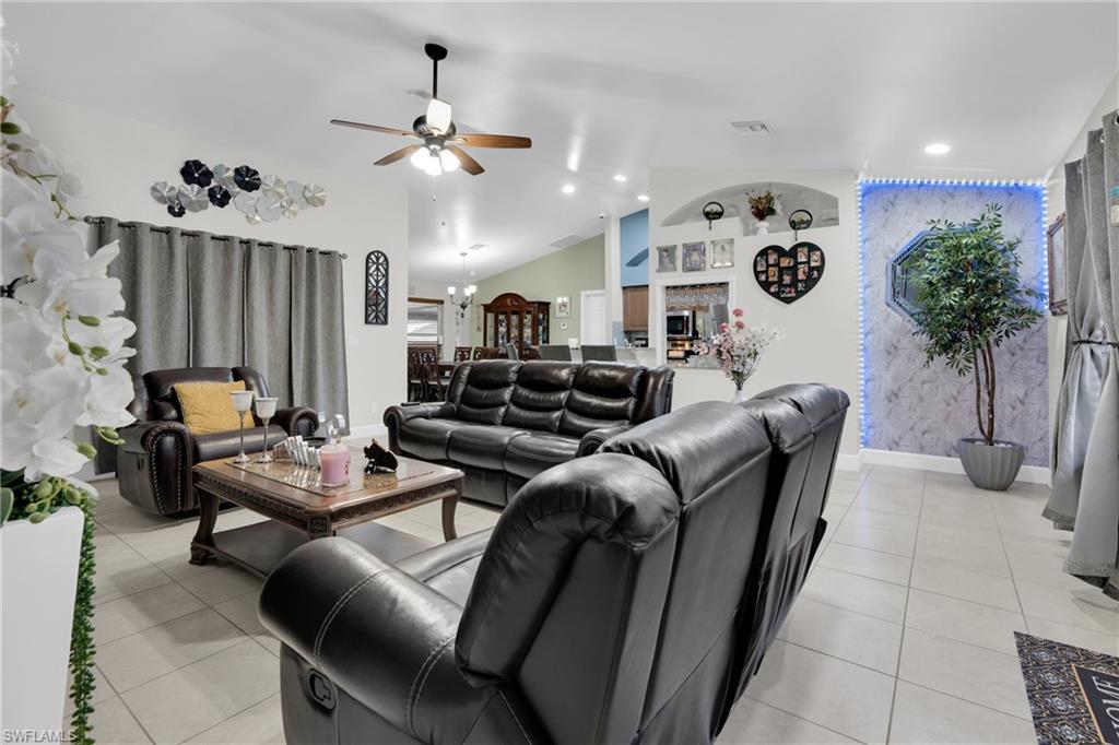 Living area with light tile patterned flooring, ceiling fan, lofted ceiling, recessed lighting, and a fireplace
