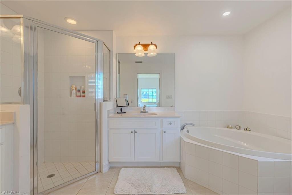 Full bath featuring a shower stall, vanity, a bath, light tile patterned floors, and recessed lighting