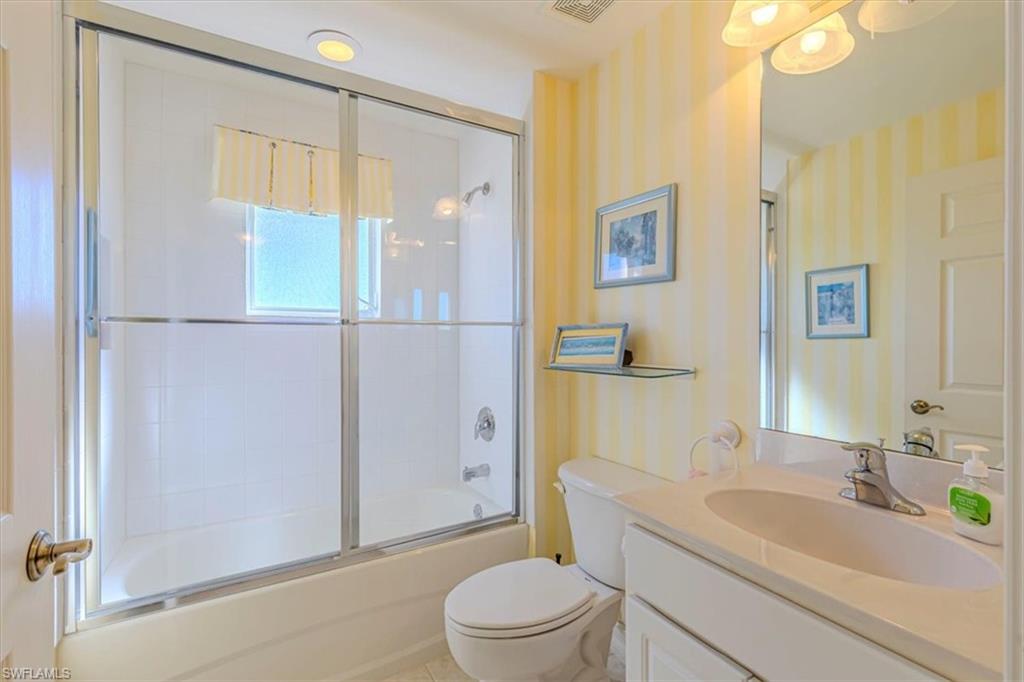 Bathroom with vanity and combined bath / shower with glass door
