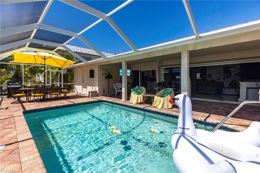 Pool with screen enclosure, outdoor dining space, and a patio area