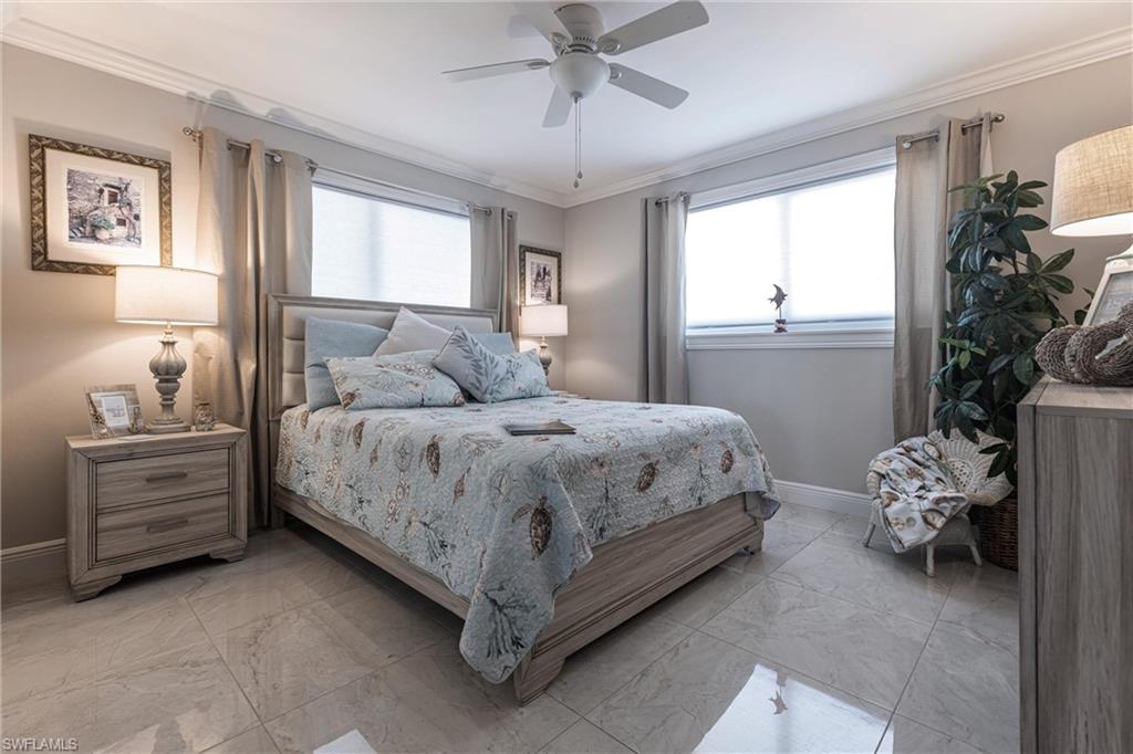Bedroom with marble finish floor, baseboards, crown molding, and a ceiling fan