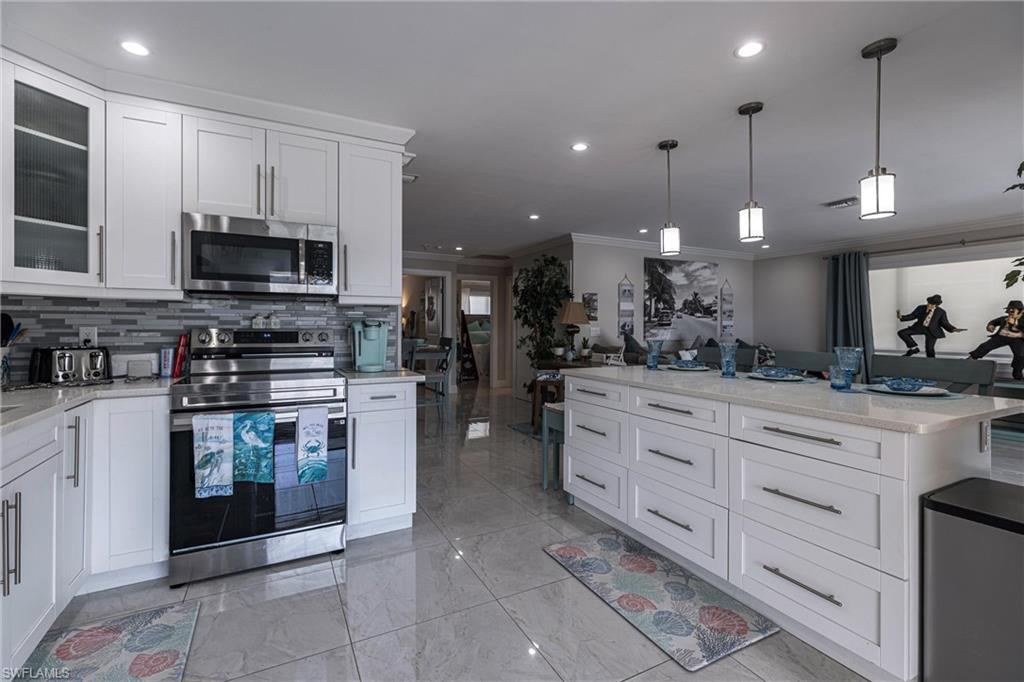 Kitchen featuring marble finish floor, ornamental molding, tasteful backsplash, appliances with stainless steel finishes, and glass insert cabinets