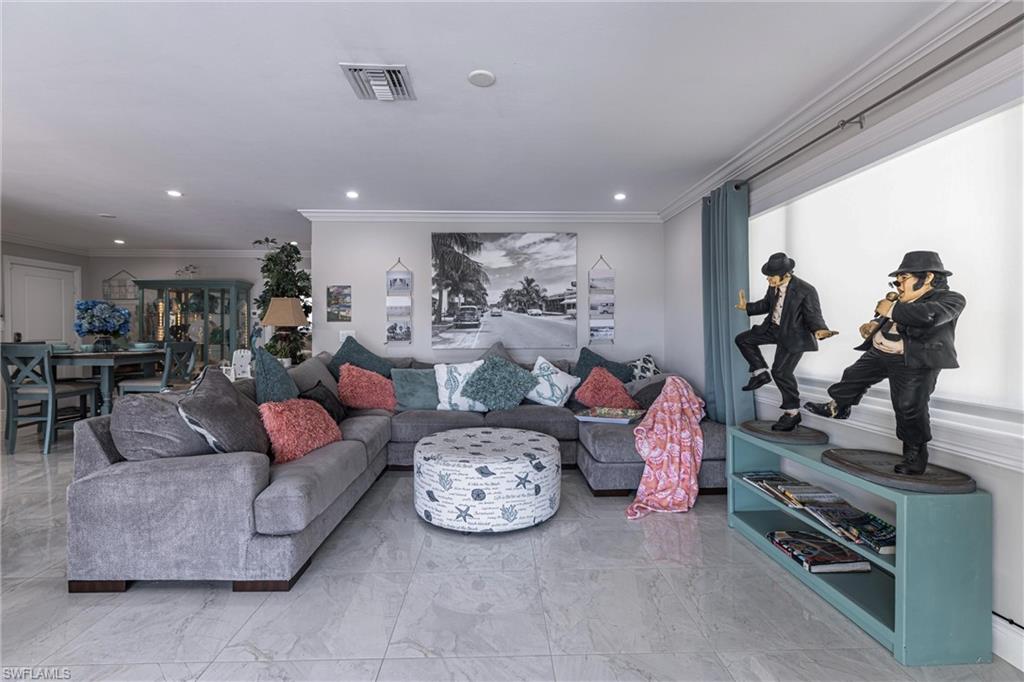 Living room featuring marble finish floor, recessed lighting, and ornamental molding