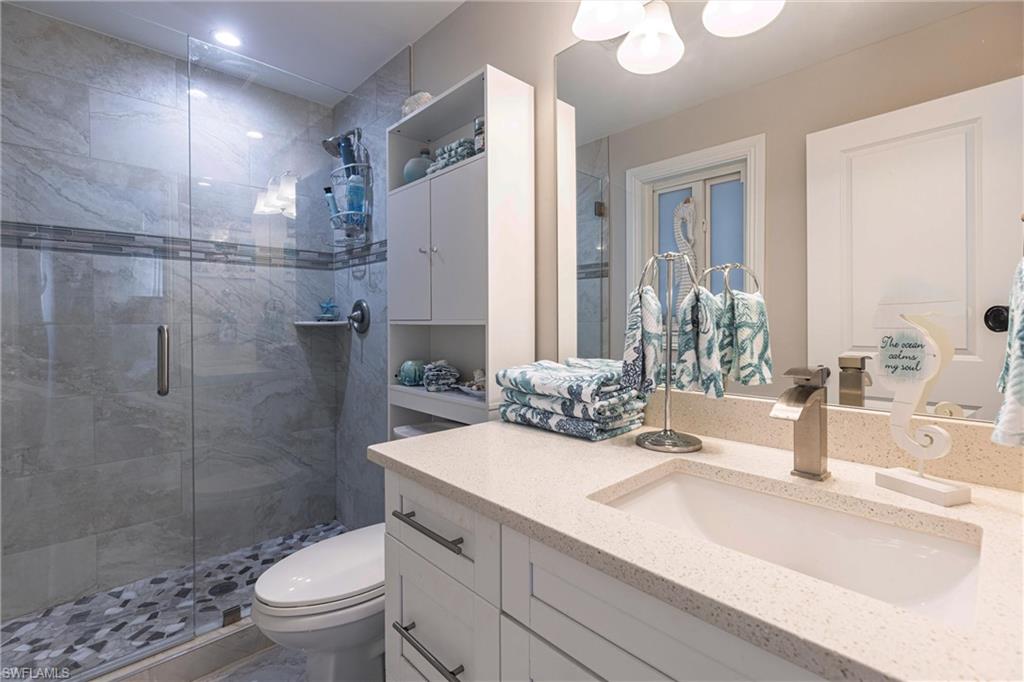 Full bathroom with a stall shower, toilet, and vanity