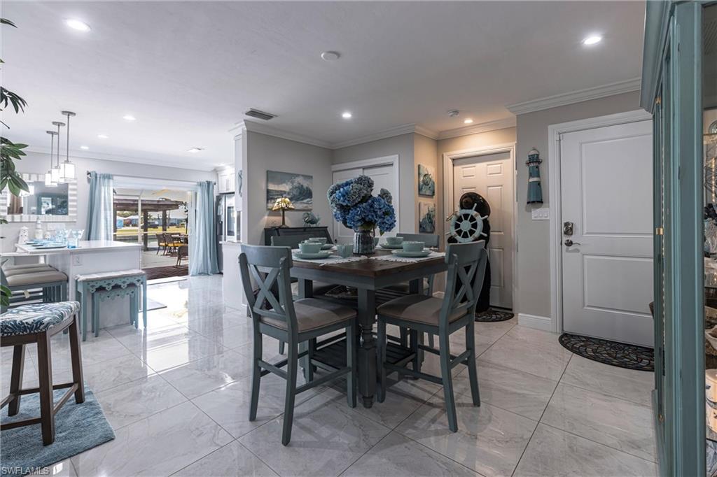 Dining room with marble finish floor, recessed lighting, and crown molding