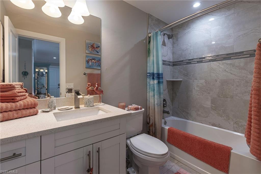 Bathroom with toilet, vanity, shower / bathtub combination with curtain