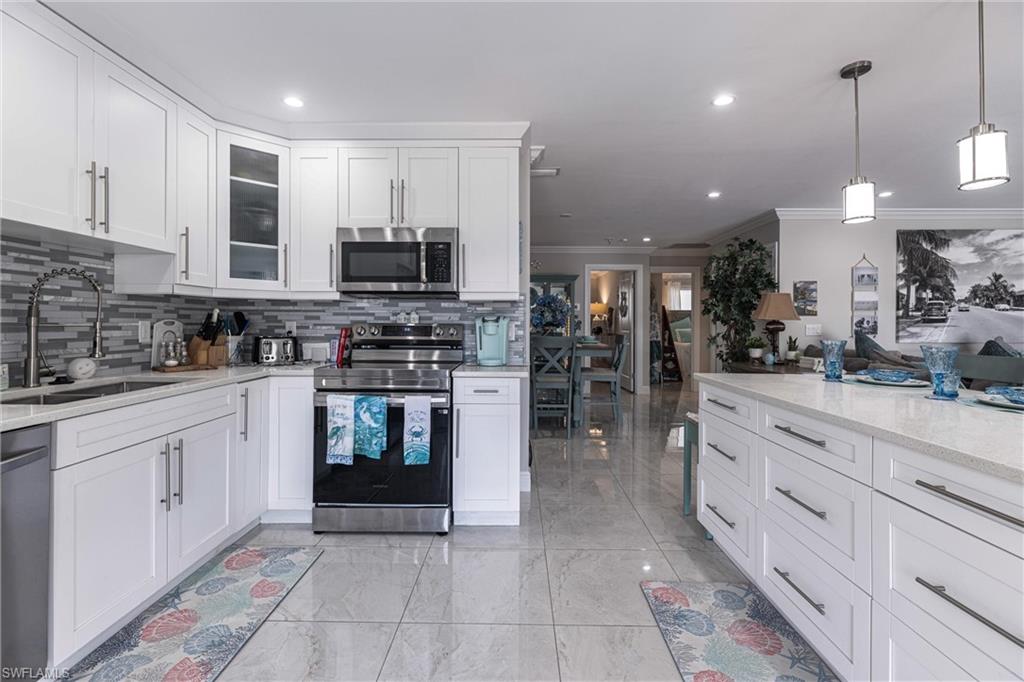 Kitchen with white cabinets, stainless steel appliances, tasteful backsplash, glass insert cabinets, and a sink