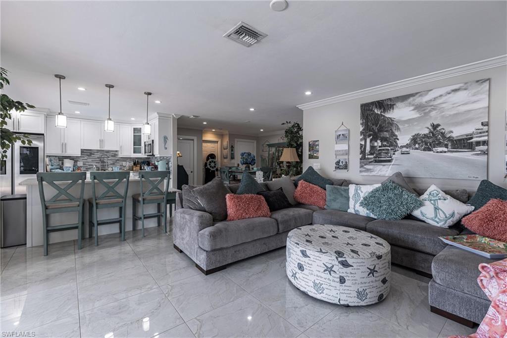 Living room with marble finish floor, recessed lighting, ornamental molding
