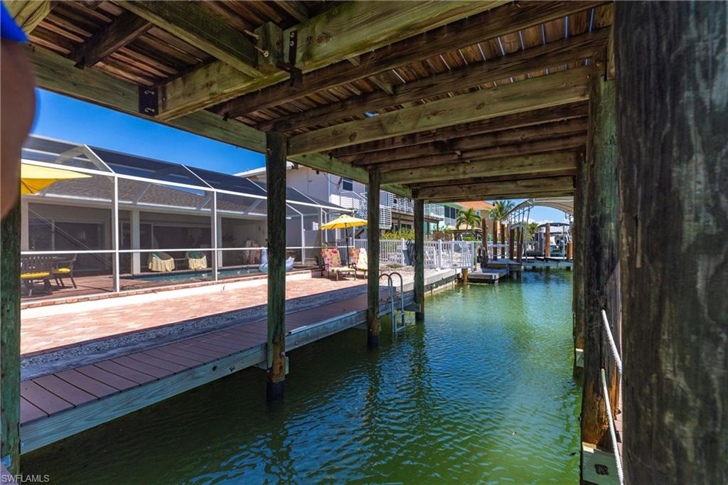 Dock area featuring a water view, a lanai, and an outdoor pool