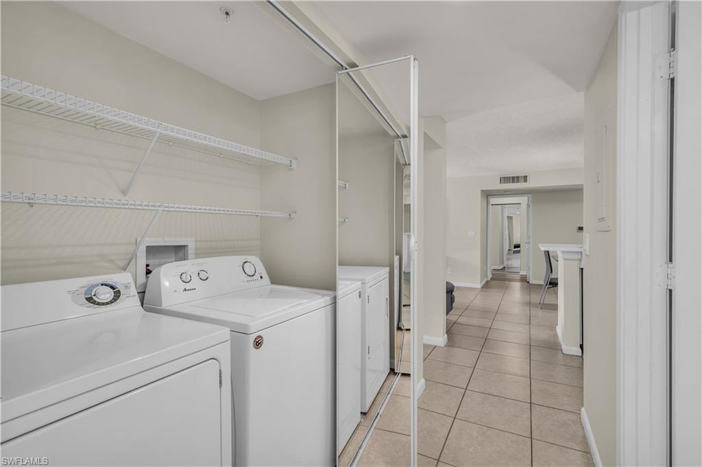Laundry area featuring separate washer and dryer and light tile patterned flooring