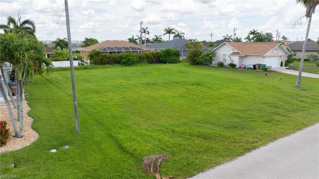 View of grassy yard featuring driveway and a residential view