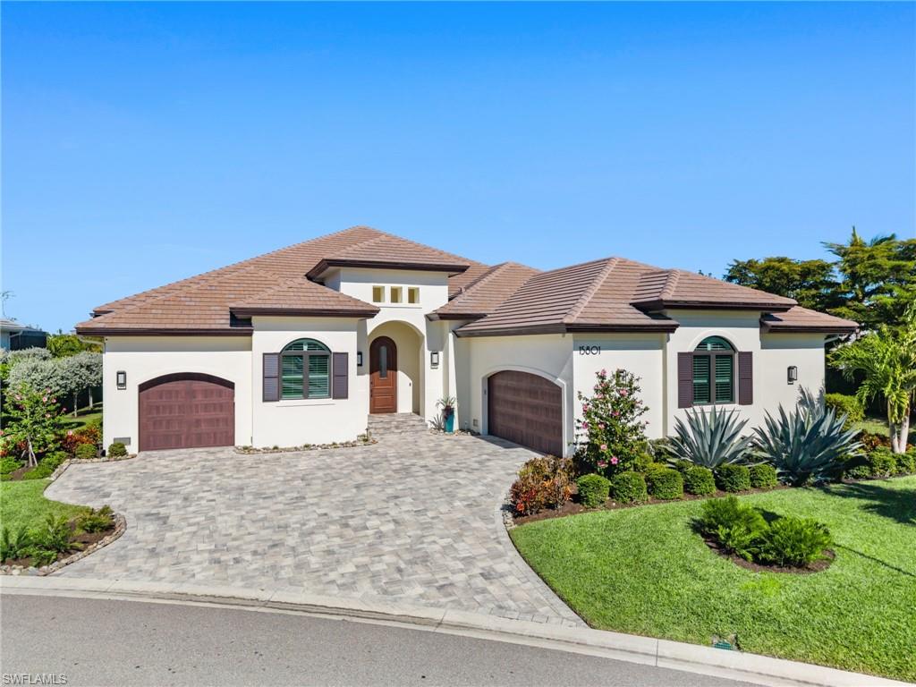 Mediterranean / spanish house featuring an attached garage, decorative driveway, a front yard, and stucco siding