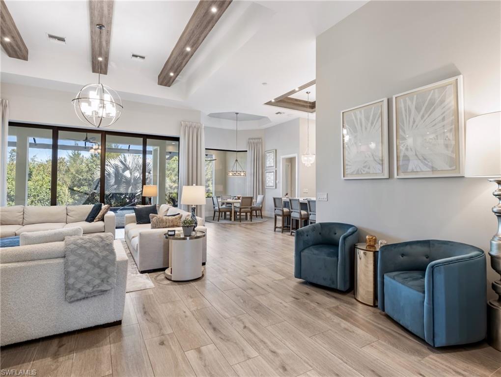 Living area with a tray ceiling, light wood-style flooring, a chandelier, and recessed lighting
