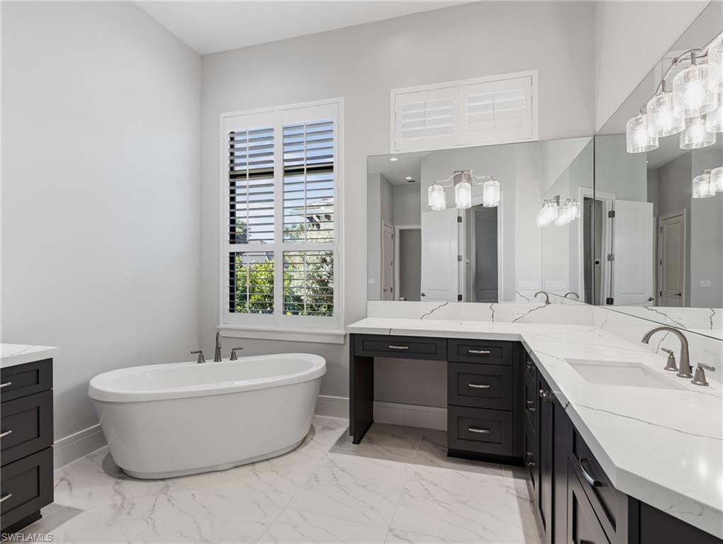 Bathroom with vanity, a freestanding bath, and light marble finish flooring