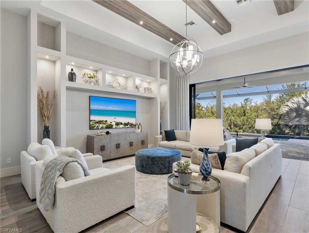 Living area with built in features, wood finished floors, recessed lighting, a towering ceiling, and a chandelier