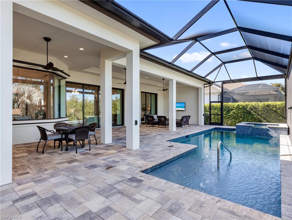View of pool with outdoor dining space, a sunroom, a patio, a pool with connected hot tub, and a lanai