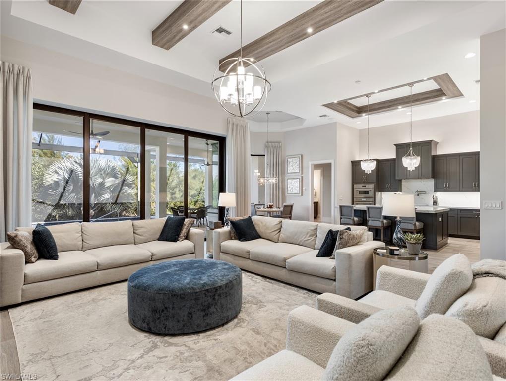 Living area with a tray ceiling, a high ceiling, recessed lighting, and a chandelier