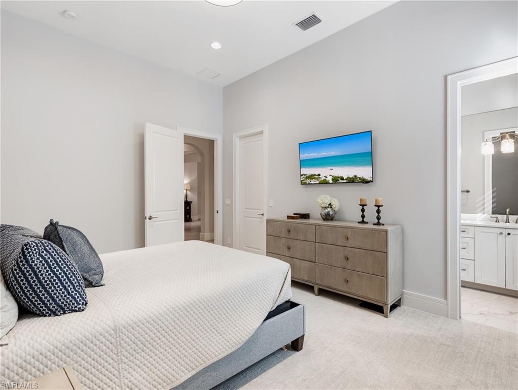 Bedroom featuring light colored carpet, recessed lighting, and ensuite bath