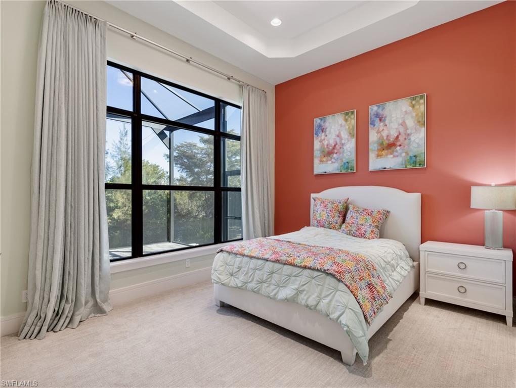 Bedroom with light carpet, a tray ceiling, and recessed lighting