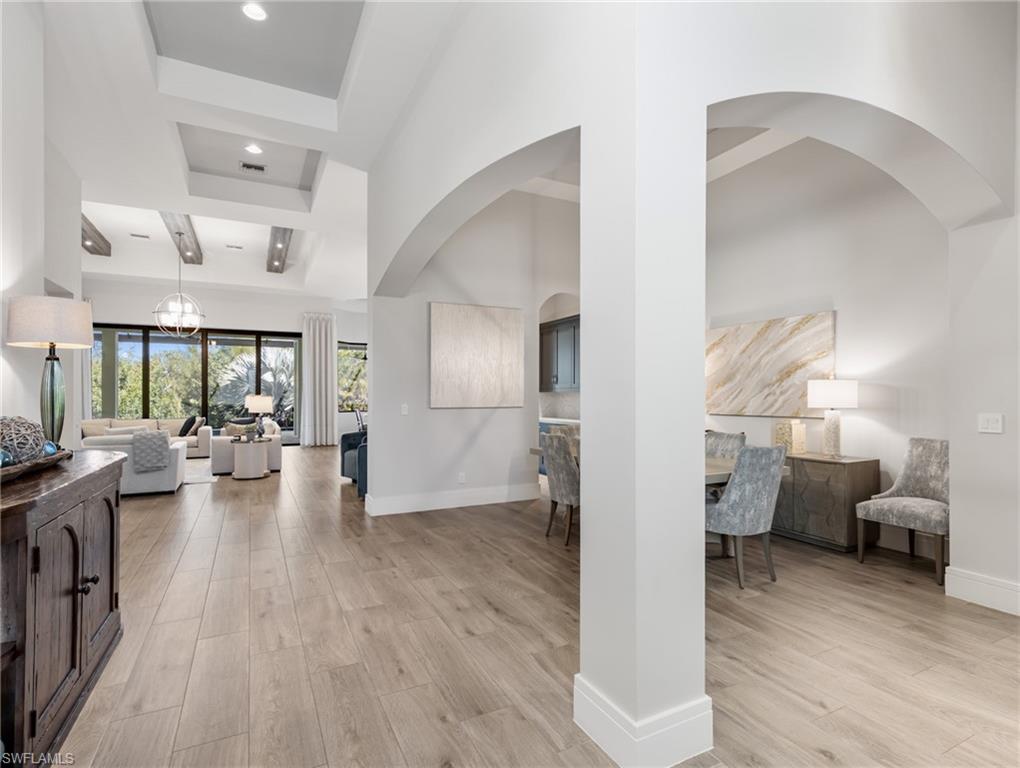 Hall with light wood-type flooring, a chandelier, recessed lighting, and a high ceiling