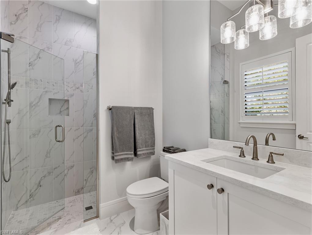 Bathroom featuring vanity, a marble finish shower, and marble look tile flooring