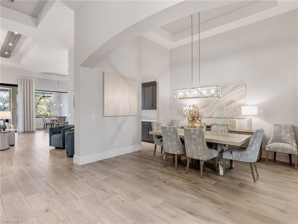 Dining space featuring light wood finished floors, a high ceiling, and a tray ceiling