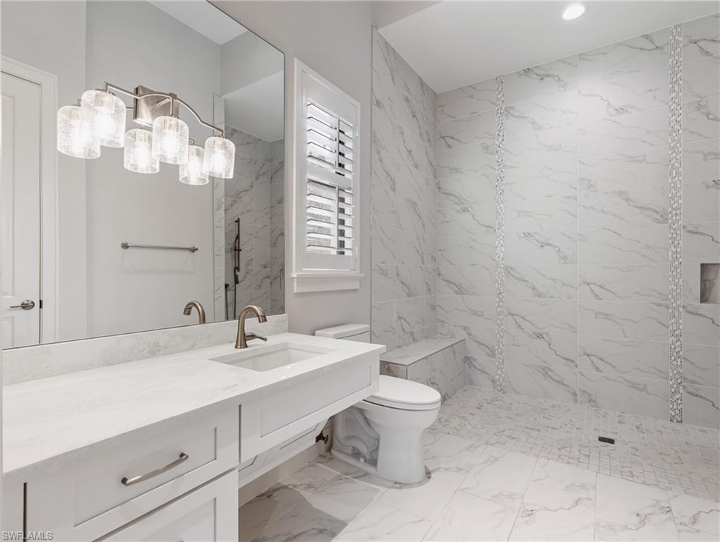 Bathroom featuring a marble finish shower, vanity, and light marble finish flooring
