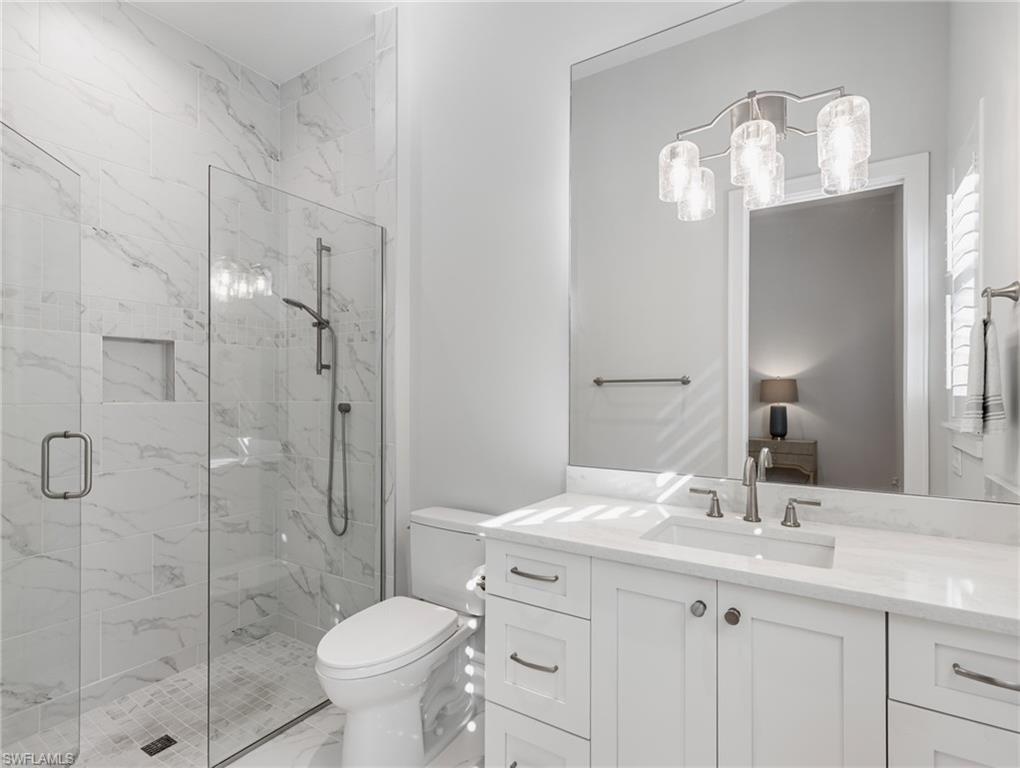 Bathroom featuring vanity, a marble finish shower, ensuite bathroom, and light marble finish flooring