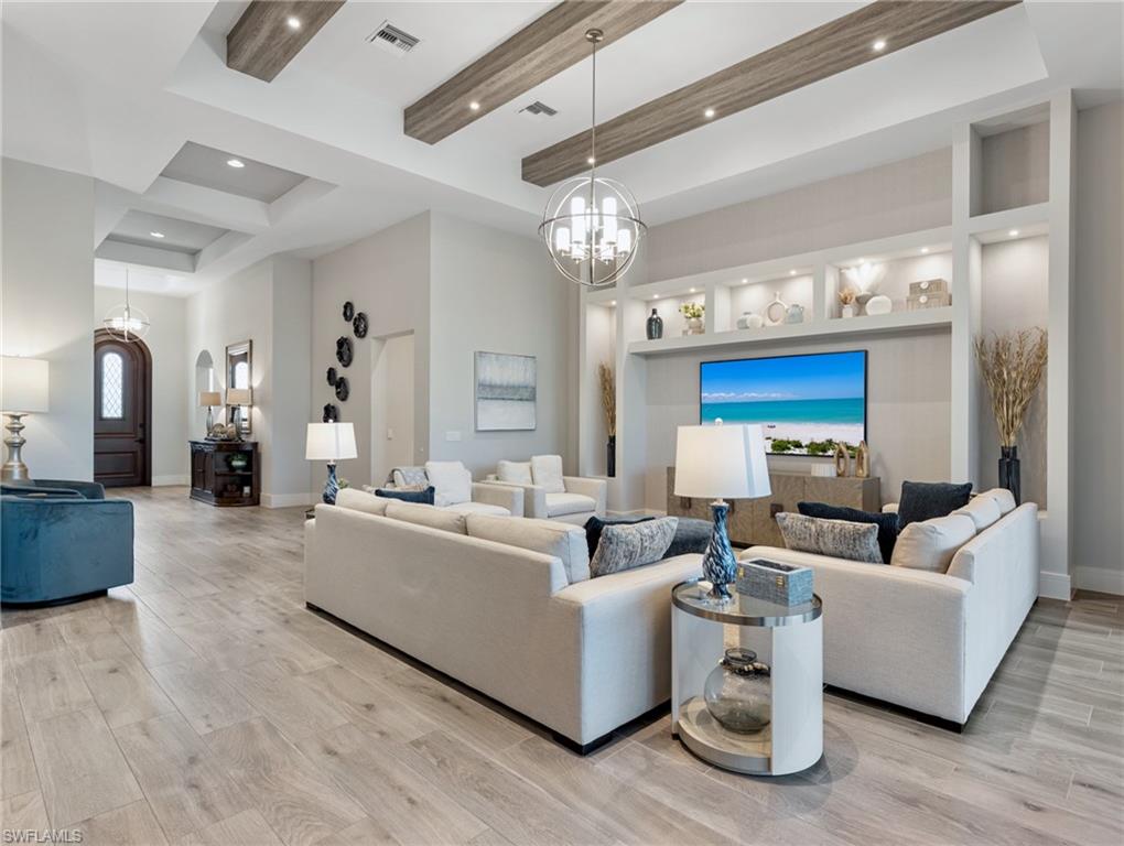 Living room with a chandelier, beamed ceiling, light wood finished floors, and recessed lighting