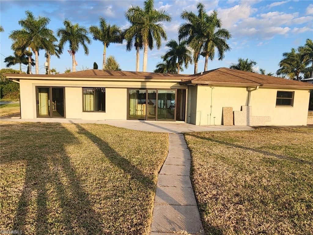 Back of property with stucco siding, a lawn, and a patio area