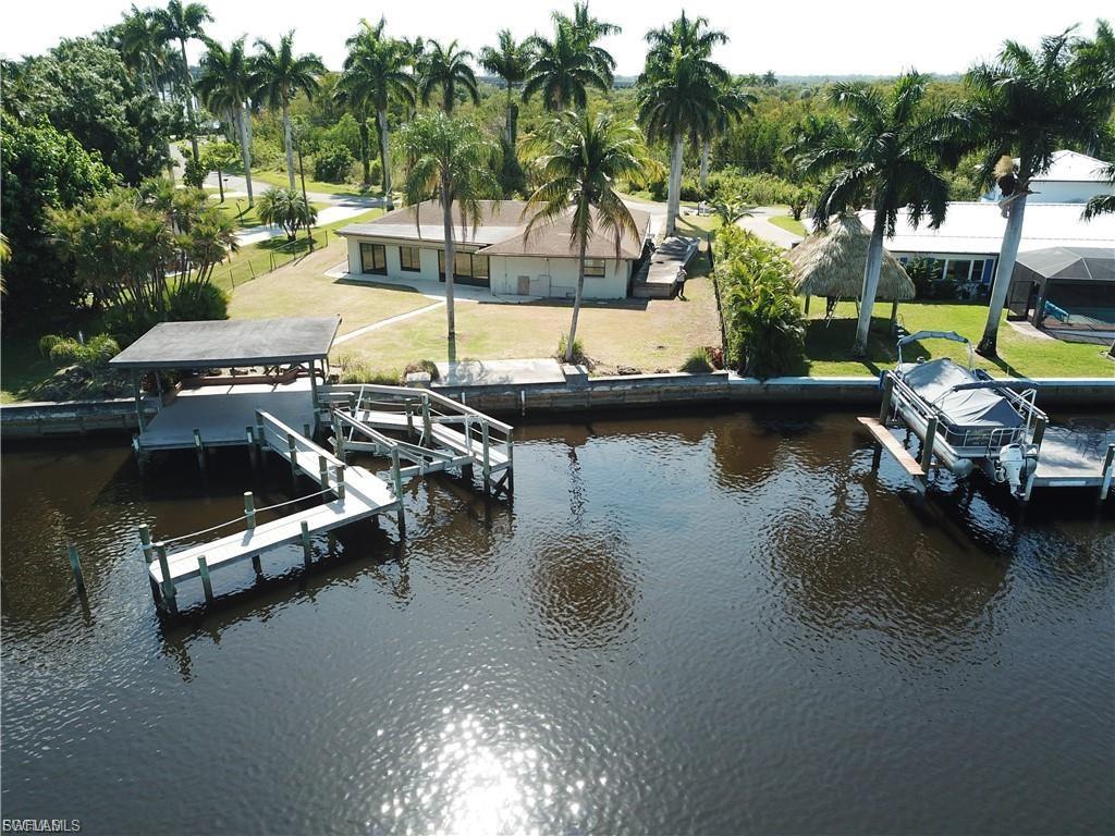 Dock featuring boat lift, a water view, and a yard