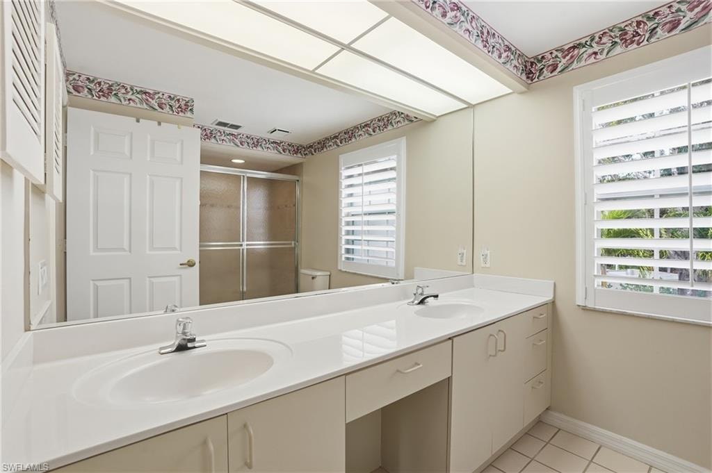 Primary Bathroom with double vanity, a stall shower, and light tile patterned floors