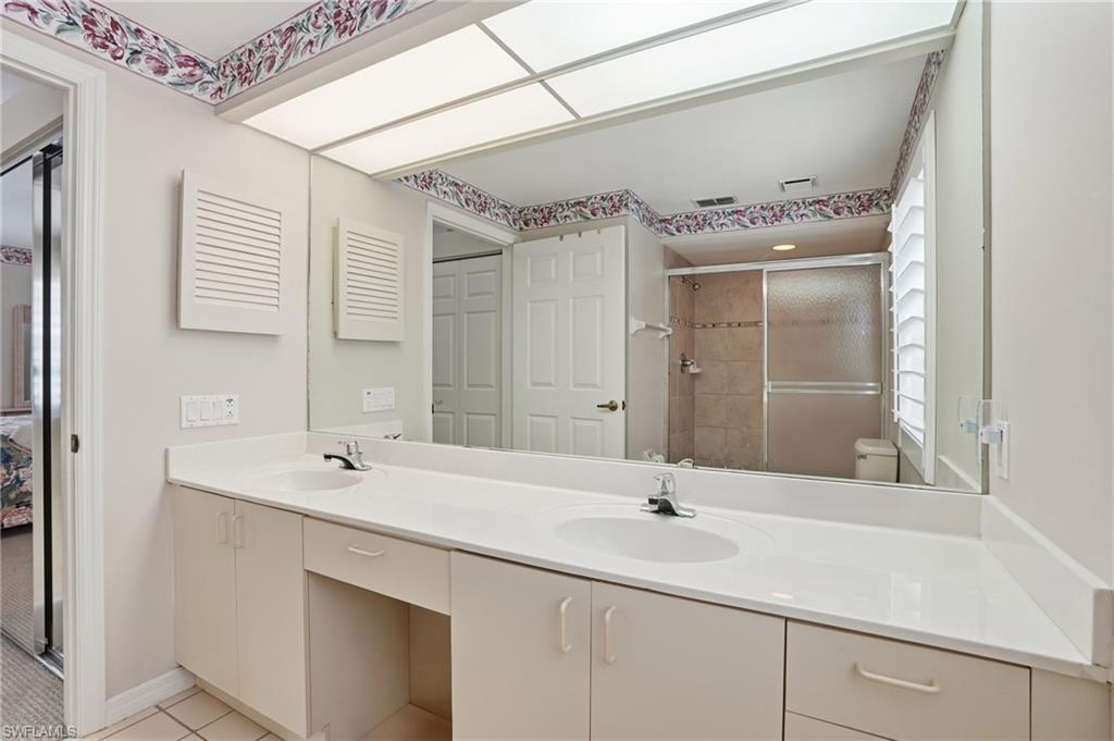 Full bath with double vanity, tiled shower, light tile patterned flooring, and ensuite bathroom
