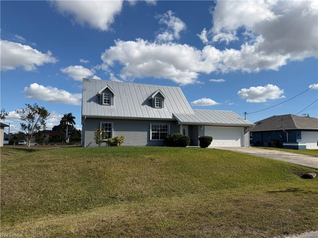 View of front of home with a metal roof, a front yard, and concrete driveway