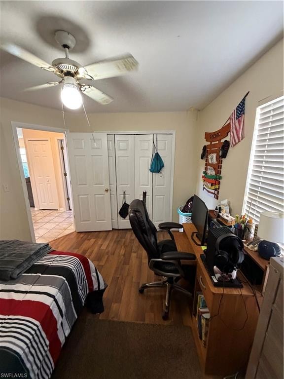Bedroom featuring an office area, ceiling fan, dark wood-type flooring, and a closet