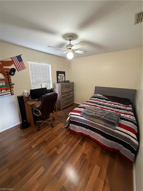 Bedroom featuring an office area, dark wood finished floors, and ceiling fan