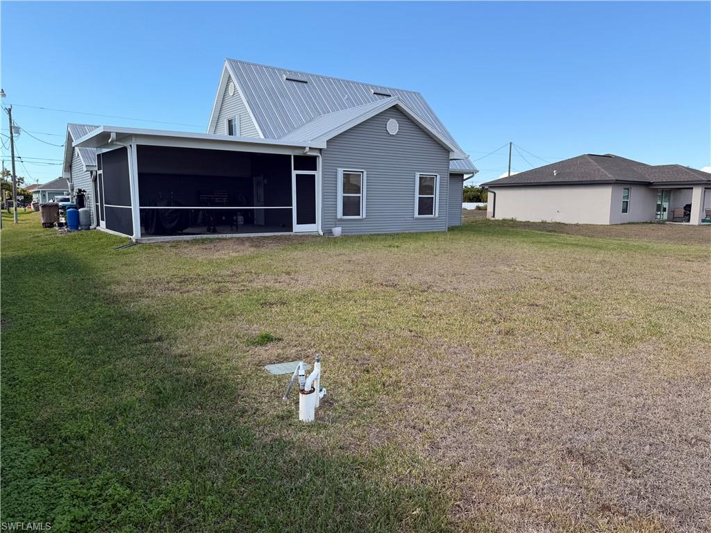 Back of house featuring a yard, a sunroom, and a metal roof