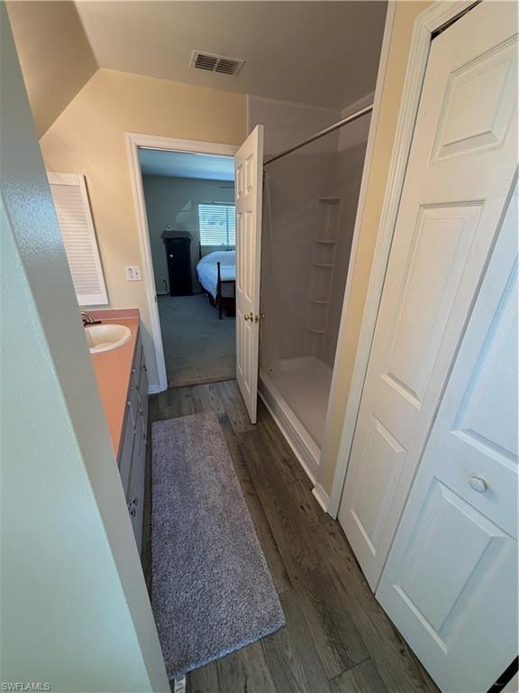 Ensuite bathroom featuring a shower stall, vanity, and dark wood-type flooring