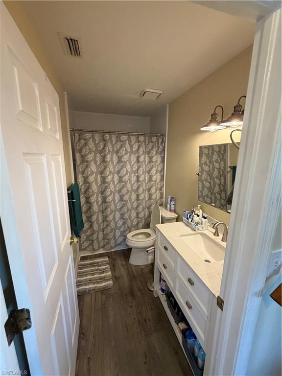 Full bath with vanity, curtained shower, and dark wood-type flooring