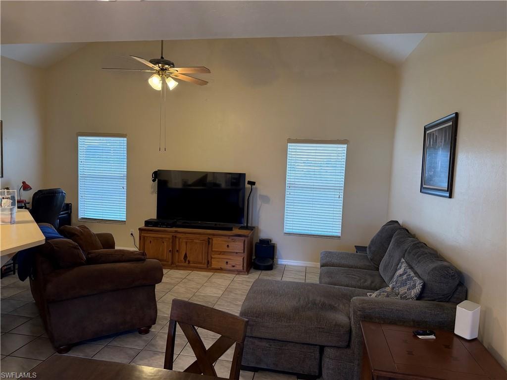 Living room featuring a ceiling fan, high vaulted ceiling, and light tile patterned flooring