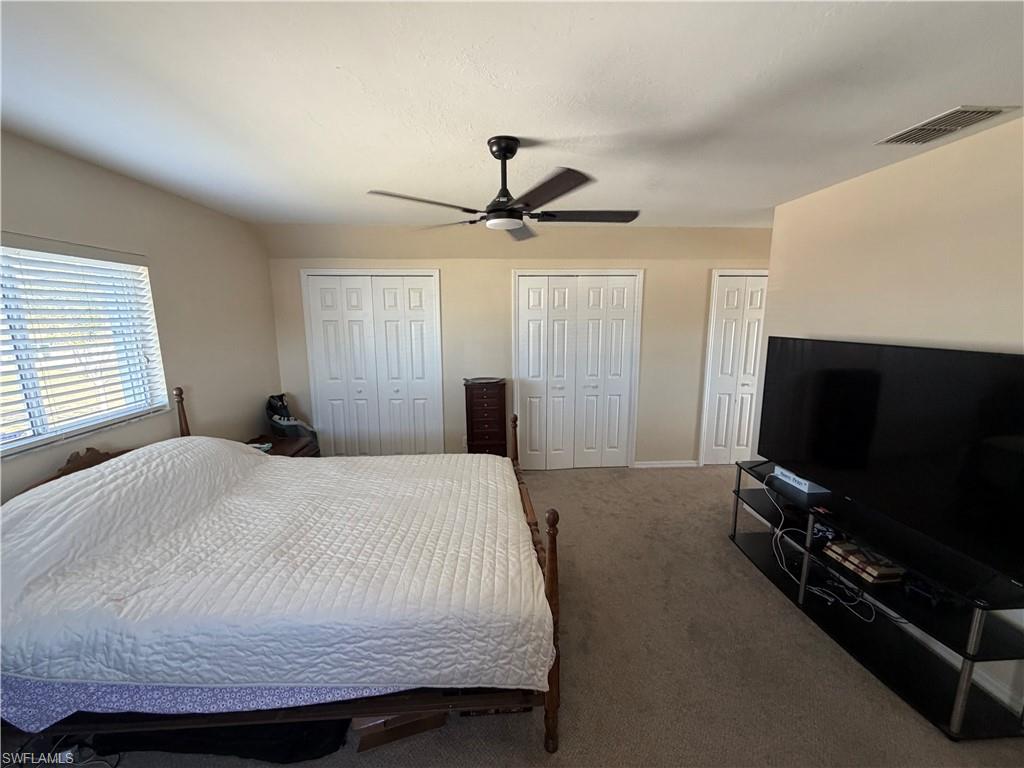 Bedroom with multiple closets, carpet, and ceiling fan