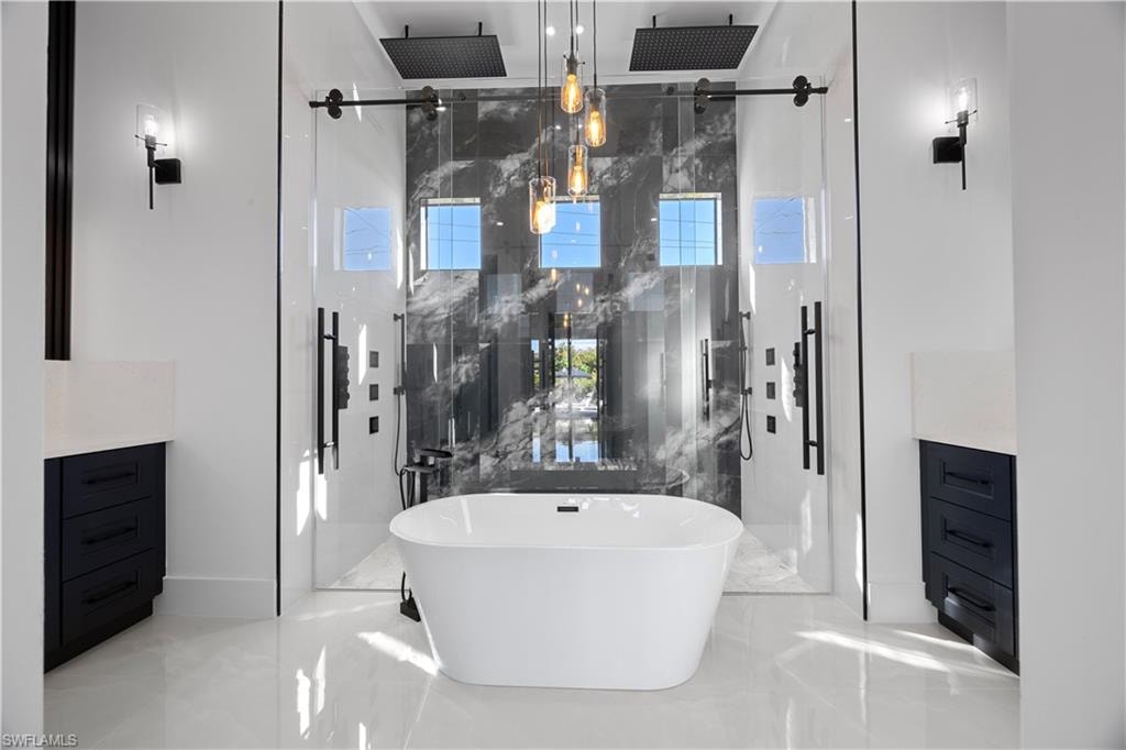 Bathroom with vanity, a freestanding bath, a marble finish shower, and light marble finish flooring