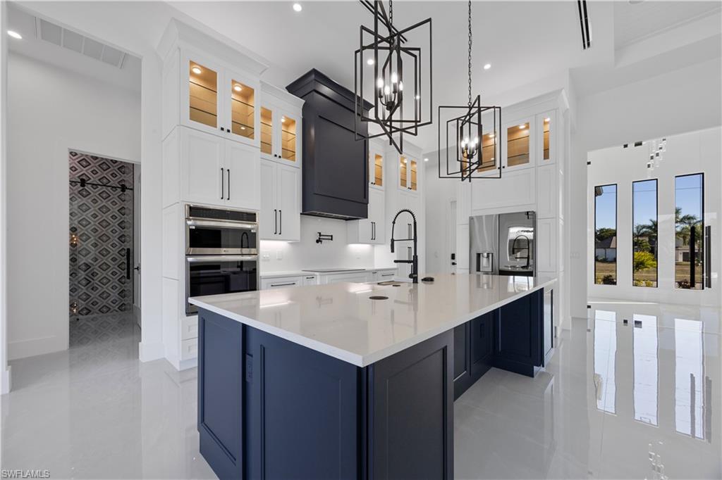 Kitchen featuring glass insert cabinets, pendant lighting, white cabinets, light stone countertops, and recessed lighting