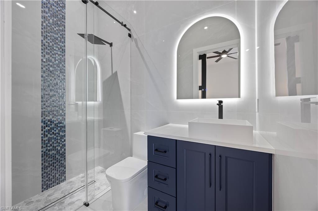 Mother in law Full bathroom featuring tile walls, a stall shower, and vanity