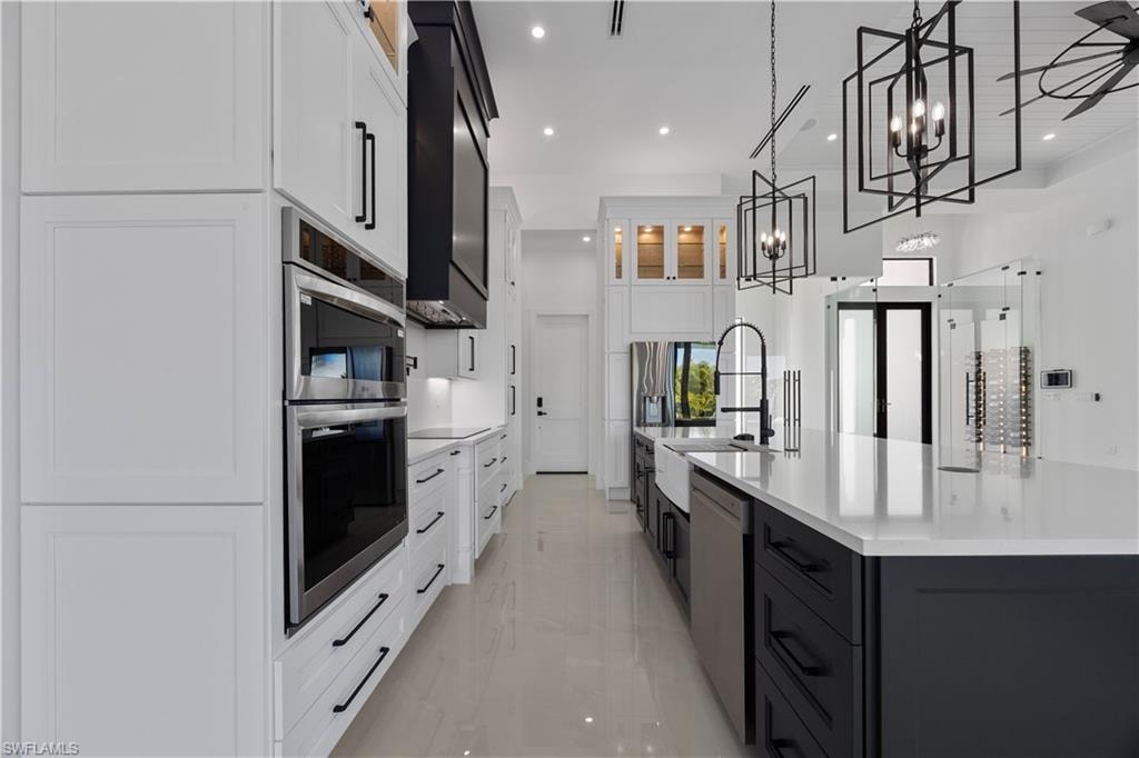 Kitchen featuring white cabinetry, glass insert cabinets, a large island, pendant lighting, and recessed lighting