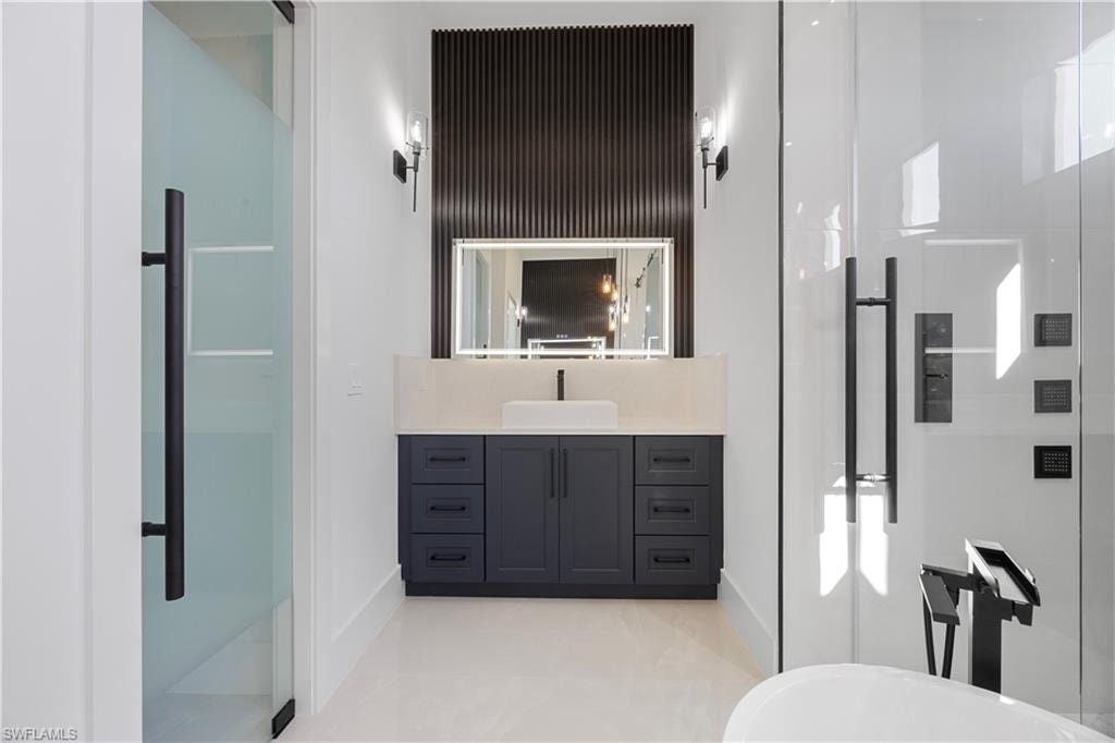 Bathroom with a stall shower, vanity, light tile patterned floors, and a freestanding tub