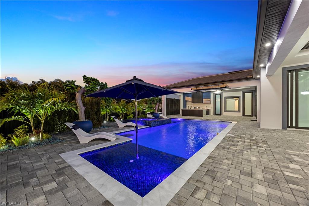 Pool at dusk with an outdoor pool, a patio, and a hot tub