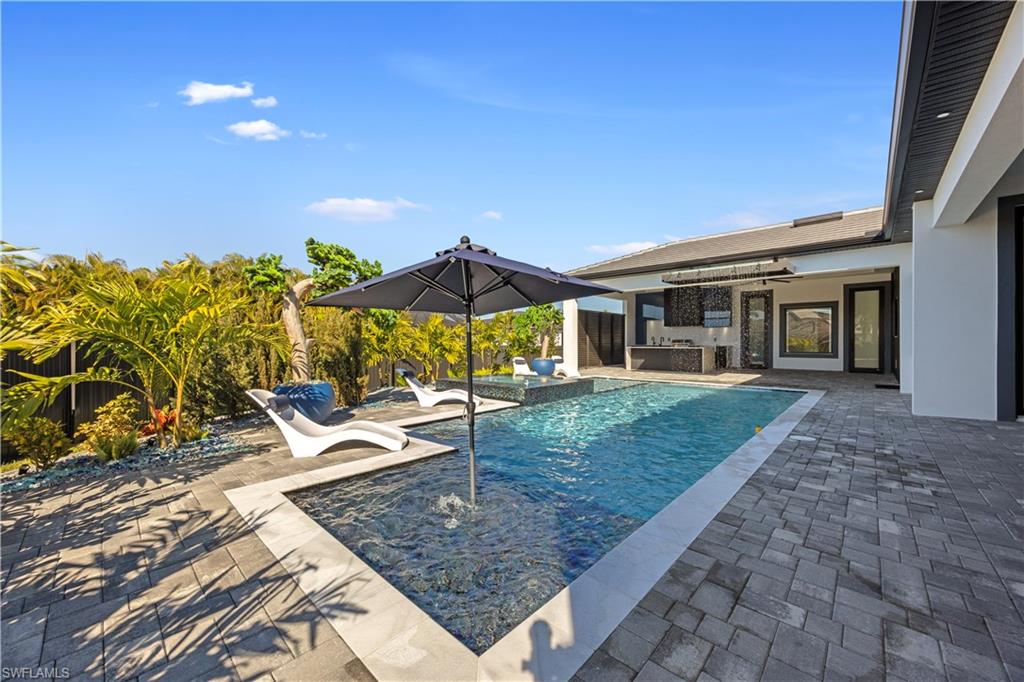 Outdoor pool with a patio area, an outdoor bar, and an outdoor kitchen