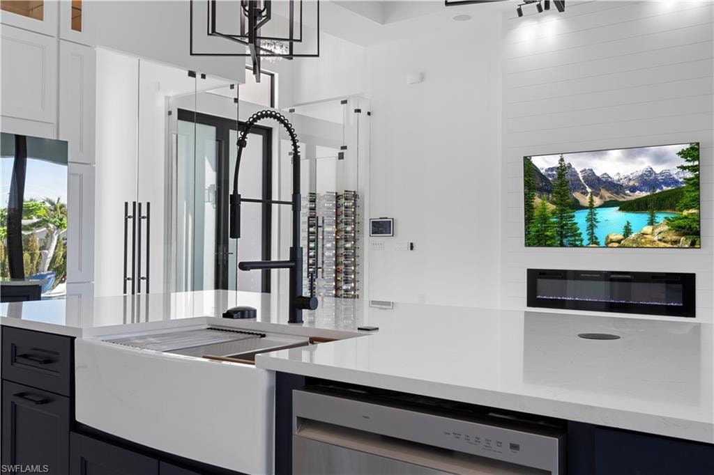 Kitchen with dishwasher, light stone countertops, and glass insert cabinets