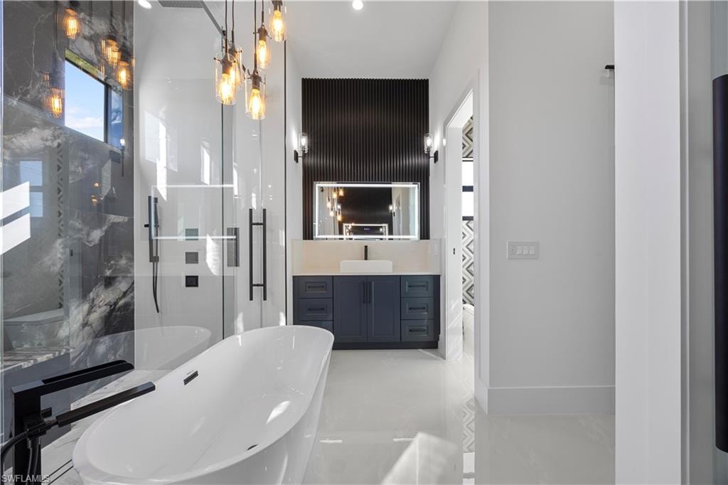 Bathroom with a marble finish shower, vanity, and a soaking tub